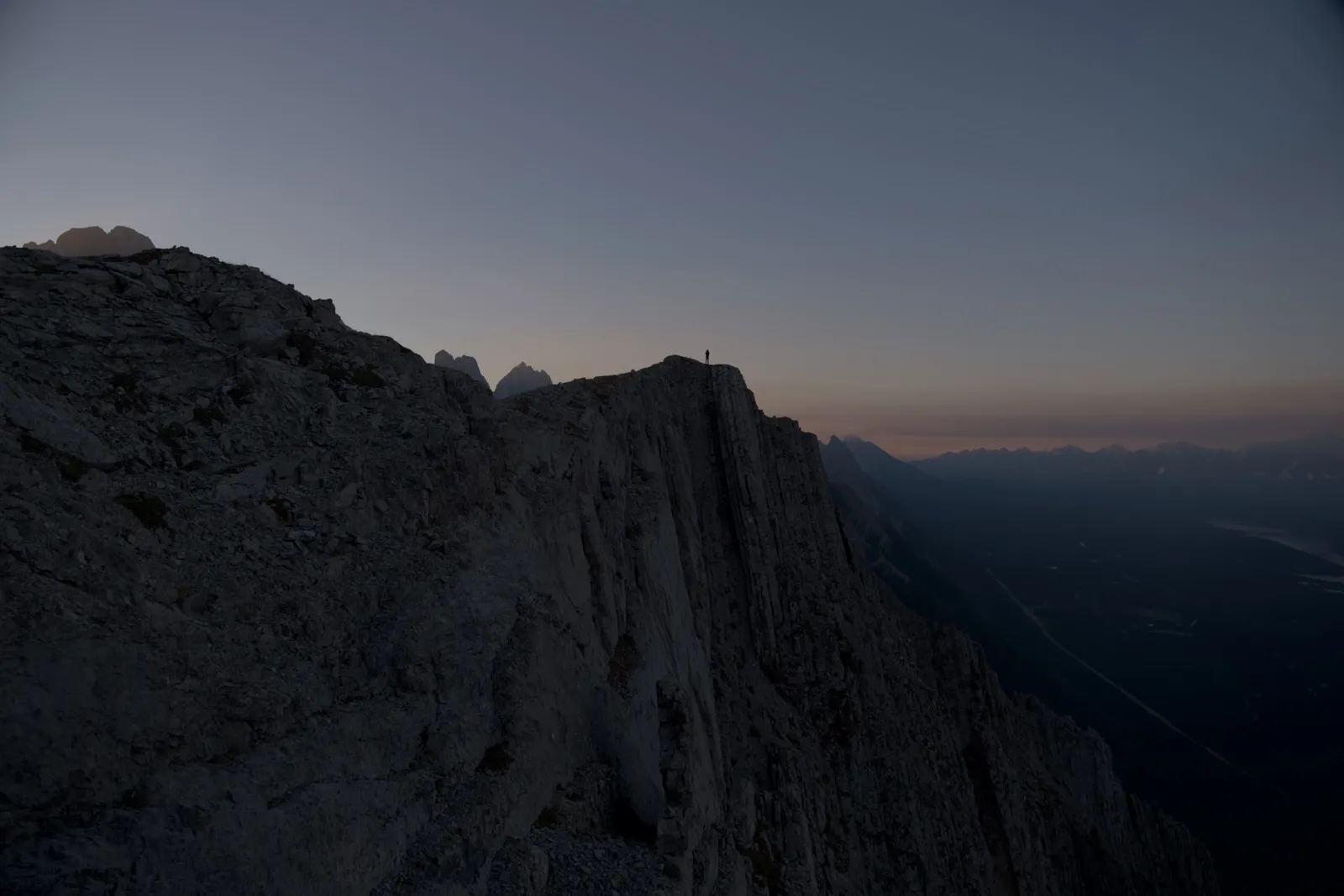 A rocky ridge at dawn, straight out of the RAW: rock face and valley almost black, grey sky