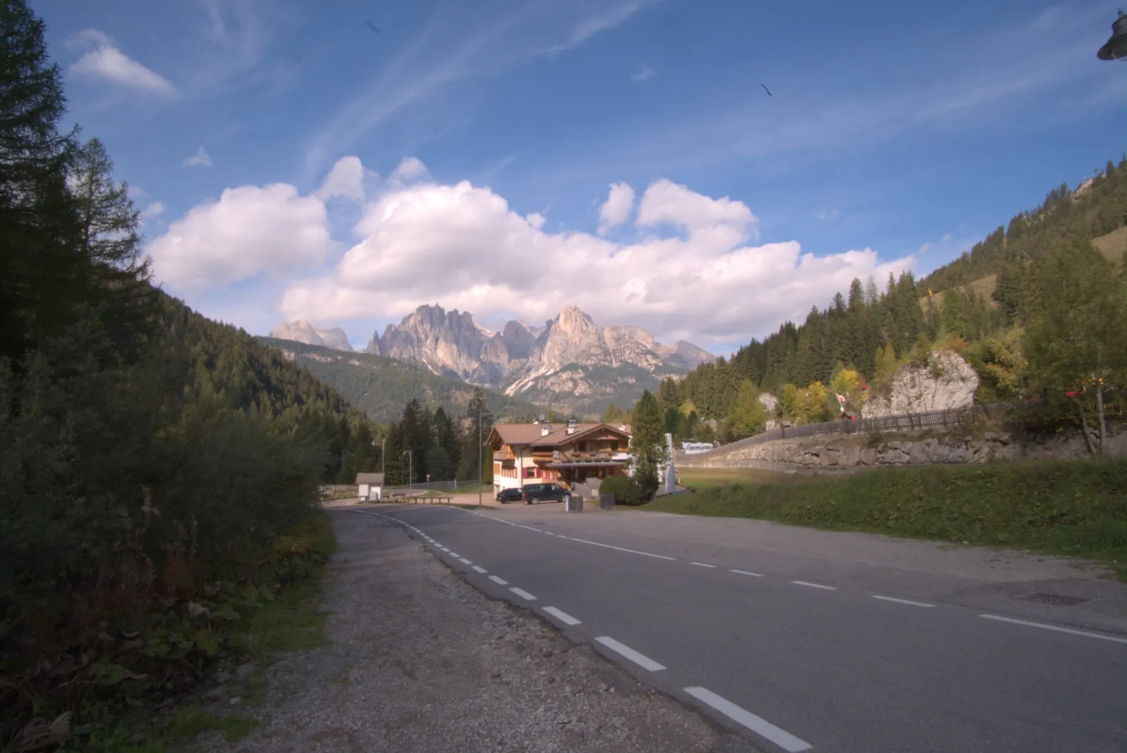 La stessa strada sviluppata: bosco, prati e case sono leggibili, nuvole e guglie restano pulite