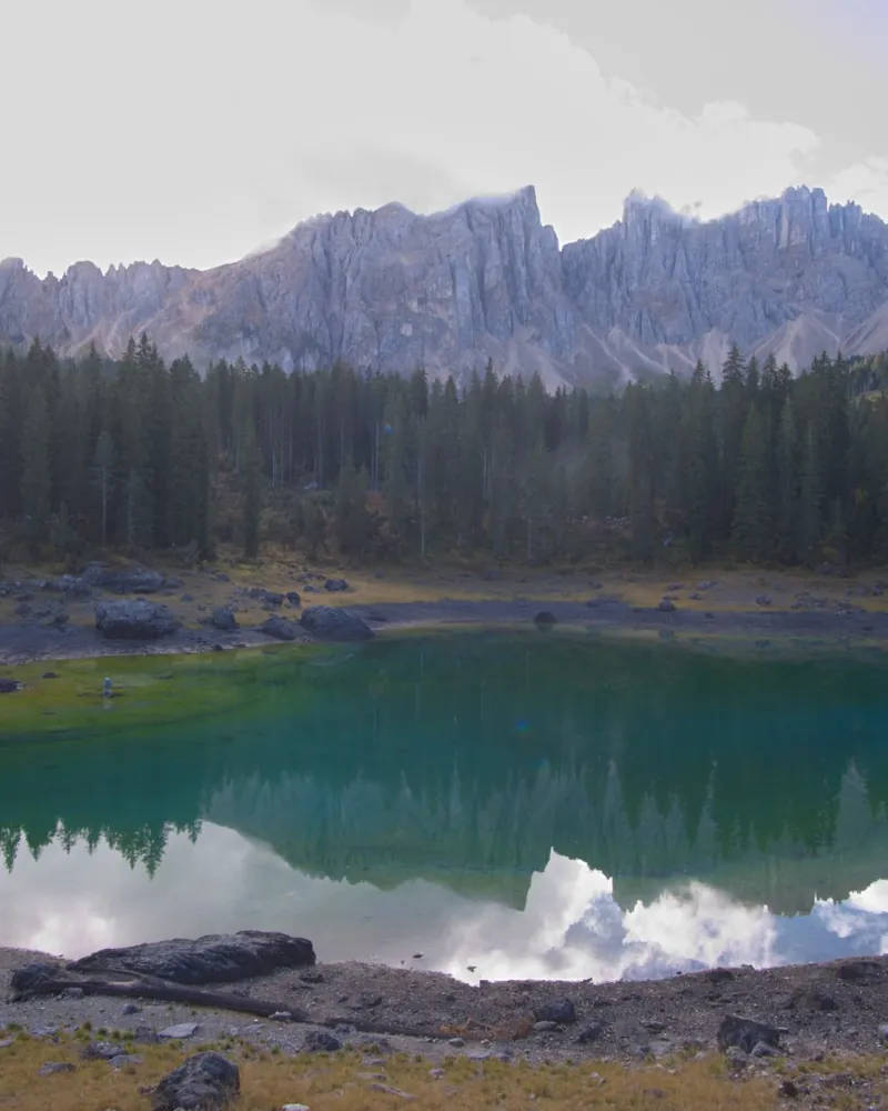 Lago turchese ai piedi di una parete di guglie dolomitiche