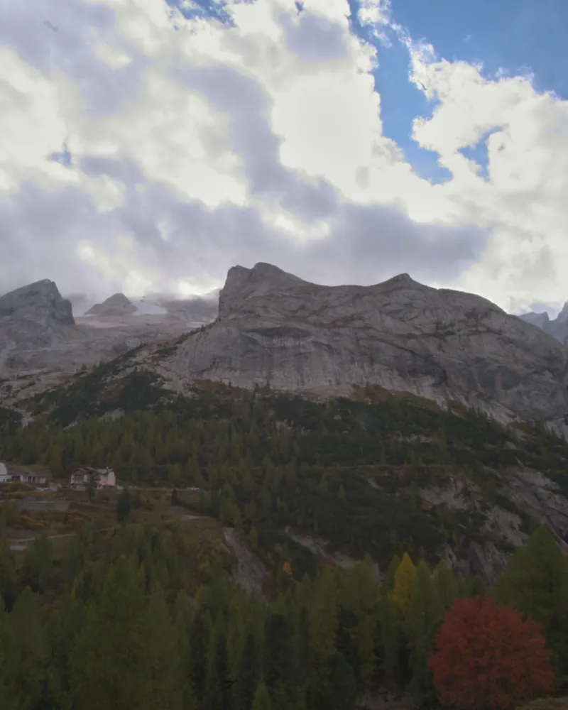 Nuvole dense sopra una parete di roccia chiara e un bosco d'autunno